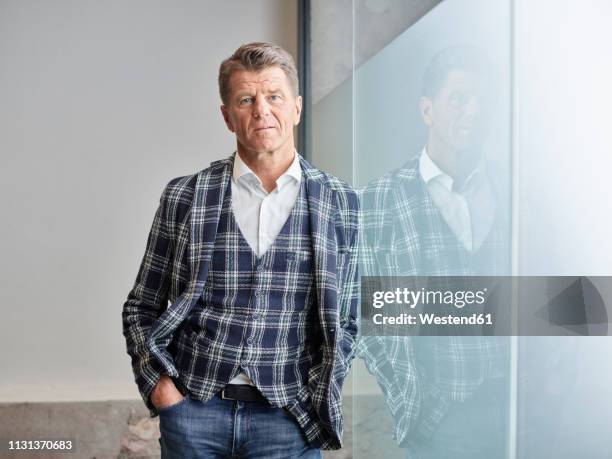 portrait of businessman leaning against glass wall - geblokt pak stockfoto's en -beelden