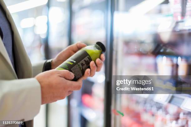 mature man in supermarket choosing smoothie from cooling shelf - holding cold drink stock pictures, royalty-free photos & images