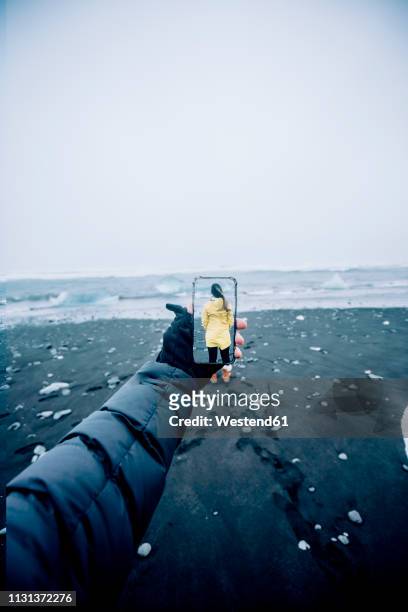 3d montage of man taking smartphone picture of iceland's landscape and woman wearing yellow raincoat - people montage stock pictures, royalty-free photos & images