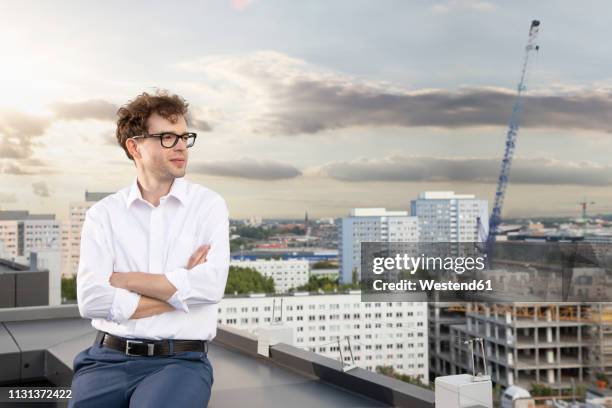 germany, berlin, content businessman on roof terrace looking at view - siteseeing stock-fotos und bilder