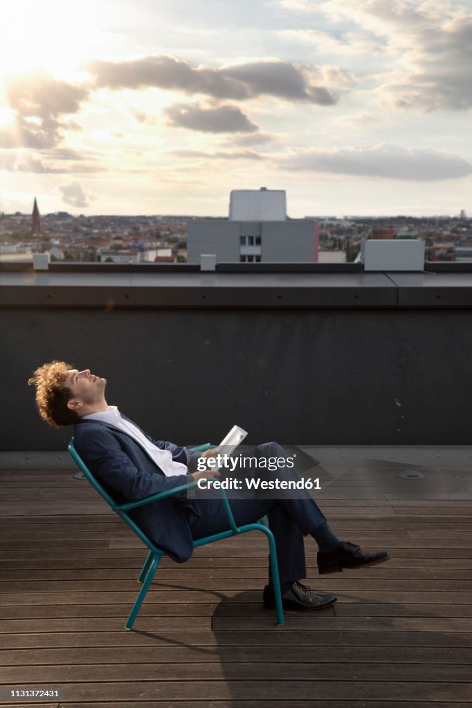 Germany, Berlin, businessman relaxing on roof terrace at sunset