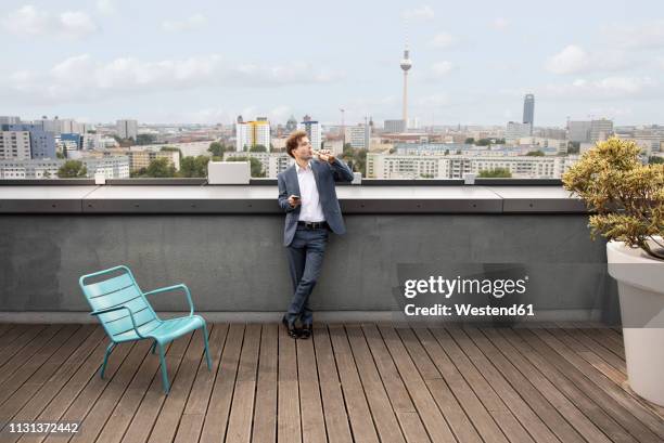 germany, berlin, businessman having a drink on roof terrace after work - television tower berlin stock pictures, royalty-free photos & images