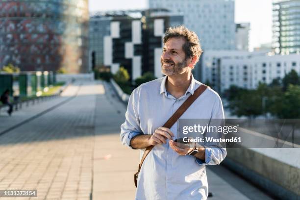 smiling mature man with cell phone in the city - mirar alrededor fotografías e imágenes de stock
