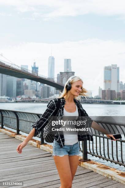 usa, new york city, brooklyn, happy young woman with headphones and cell phone dancing at the waterfront - shallow 2018 song stock pictures, royalty-free photos & images