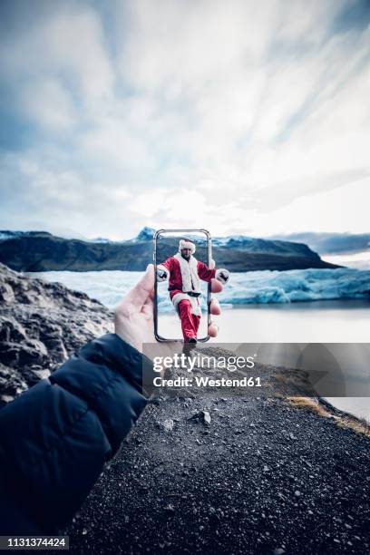 iceland, man disguised as santa claus coming out of a cell phone - travel montage stock pictures, royalty-free photos & images