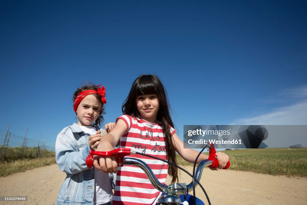 Two girls with bicycle on path in remote landscape