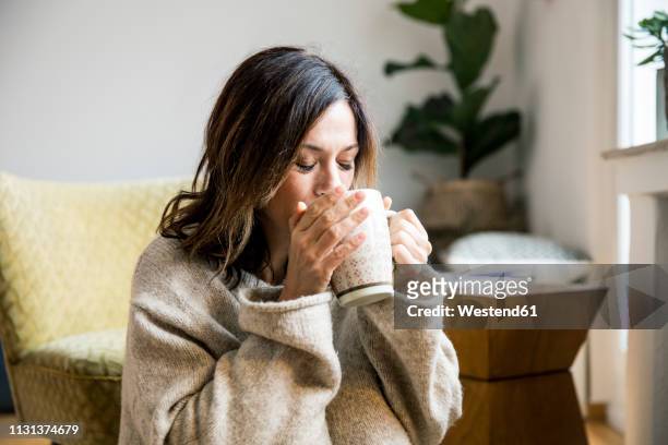 woman sitting in her comfortable home, drinking tea - tee stock-fotos und bilder
