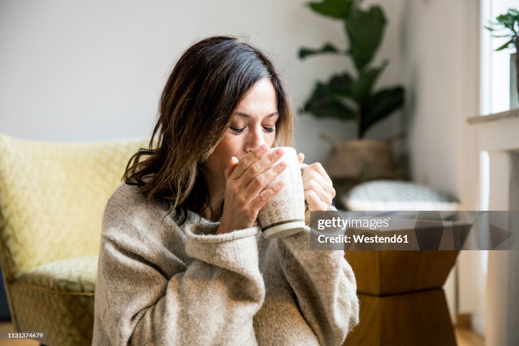 Woman sitting in her comfortable home, drinking tea