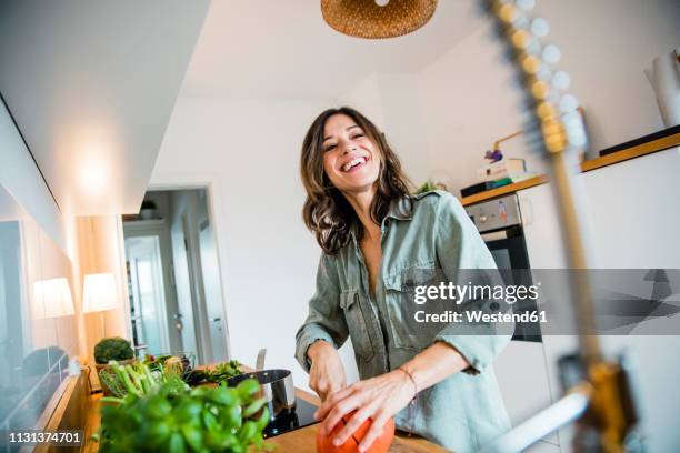 laughing woman slicing pumpkin in her kitchen - soup home foto e immagini stock