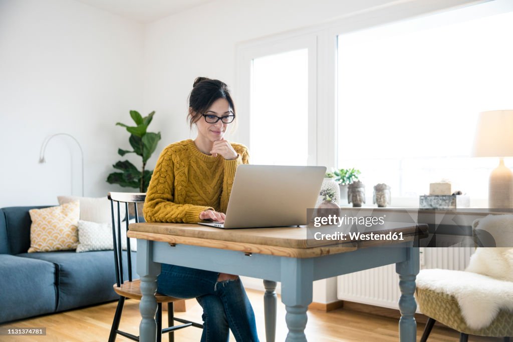 Woman sitting at table, using laptop