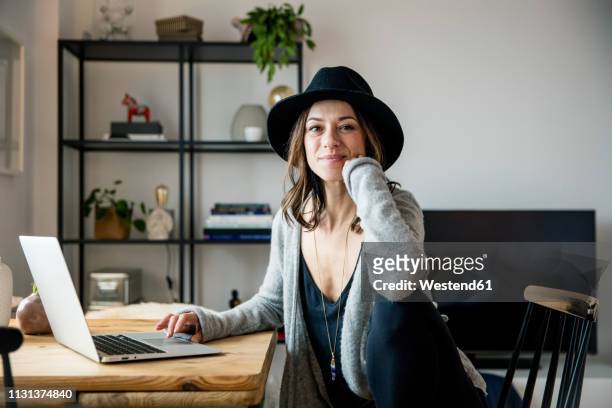 mature woman with hat, sitting at home, using laptop - woman portrait in home laptop stock pictures, royalty-free photos & images