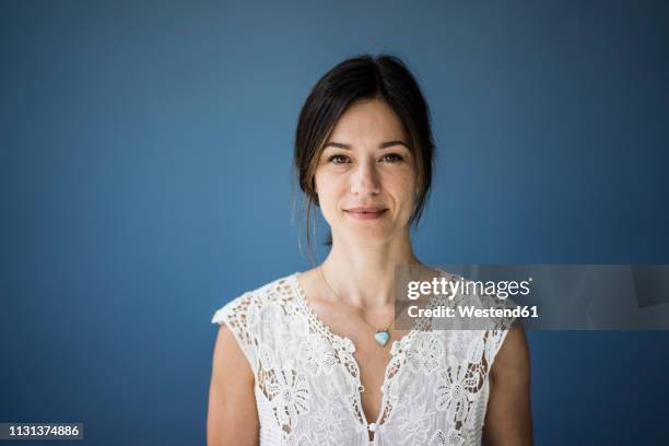 portrait of a beautiful woman against blue background - portrait blue background stock-fotos und bilder