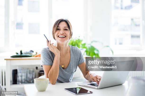 happy oman sitting at desk, working from home, using laptop - happy ipad beautiful stockfoto's en -beelden