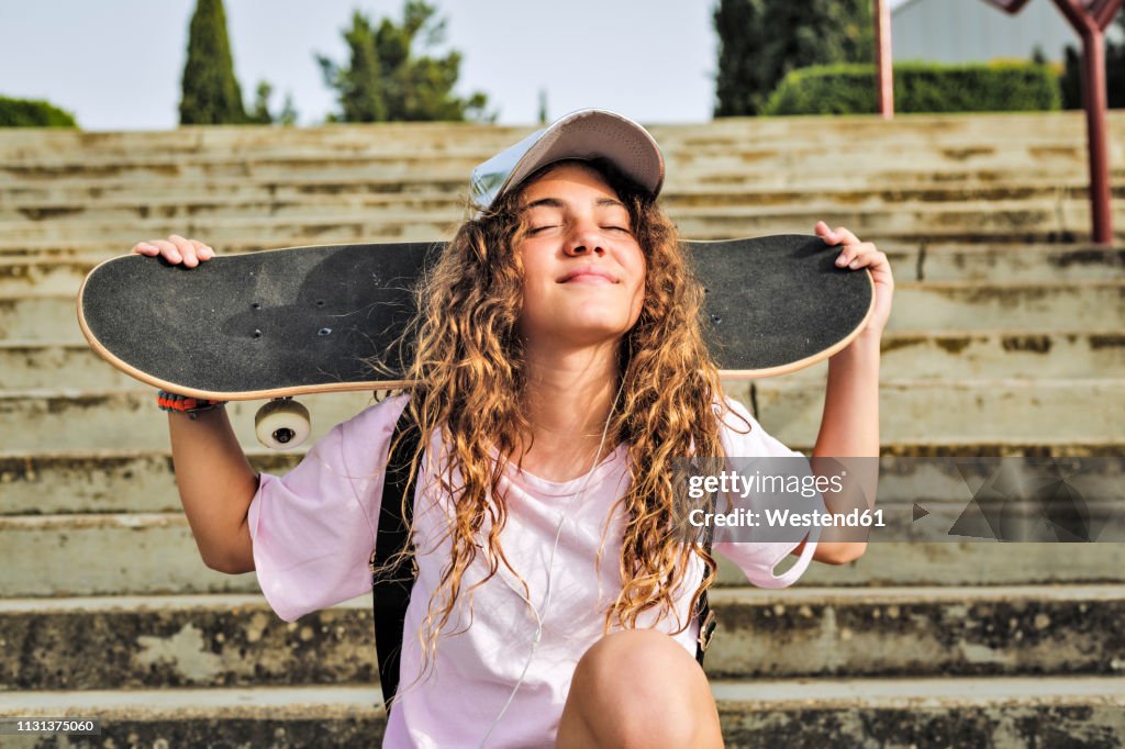 Girl with skateboard sitting on steps