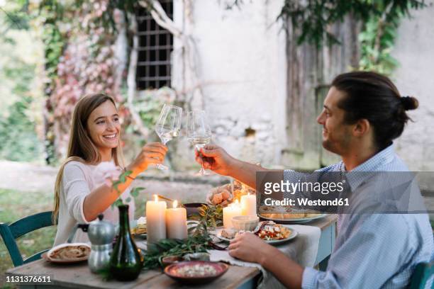 couple having a romantic candelight meal next to a cottage clinking wine glasses - burning rose bildbanksfoton och bilder