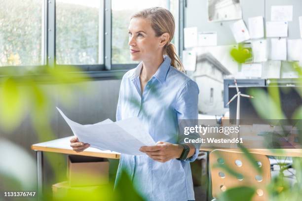 woman in office working on plan with wind turbine model on table - plan architecte photos et images de collection