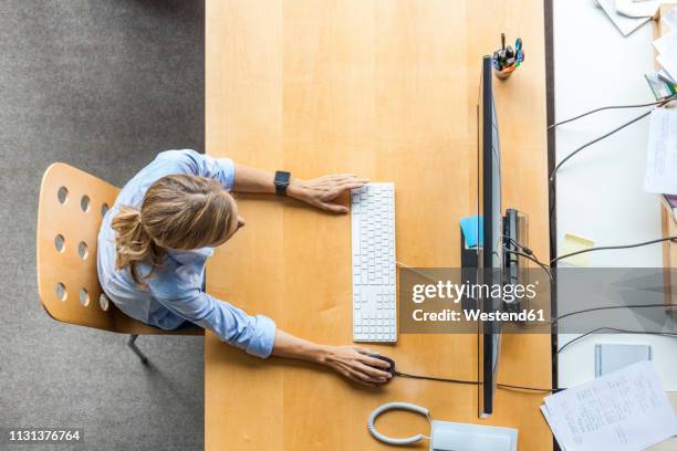 top view of woman using computer at desk in office - desk from above fotografías e imágenes de stock