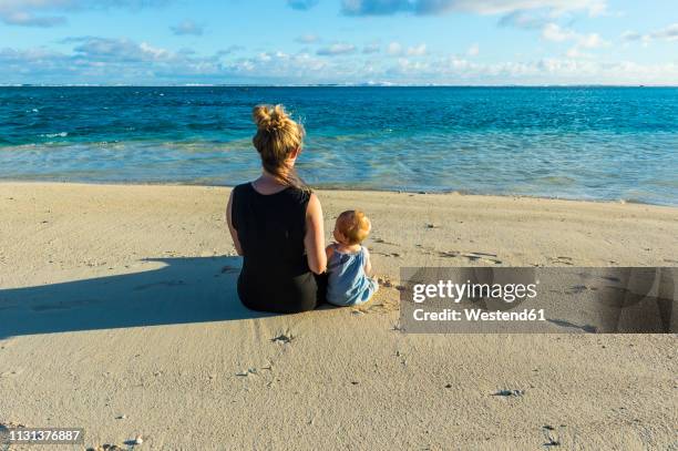 cook islands, rarotonga, woman sitting with her baby on a white sand beach - rarotonga fotografías e imágenes de stock