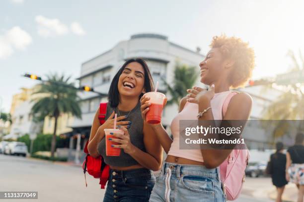 usa, florida, miami beach, two happy female friends having a soft drink in the city - amigos latinos fotografías e imágenes de stock