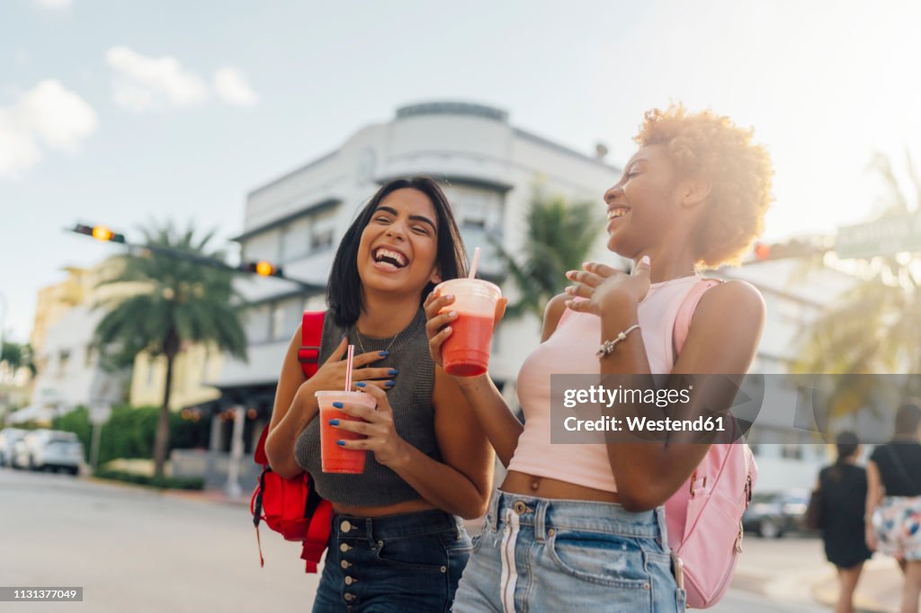 USA, Florida, Miami Beach, two happy female friends having a soft drink in the city