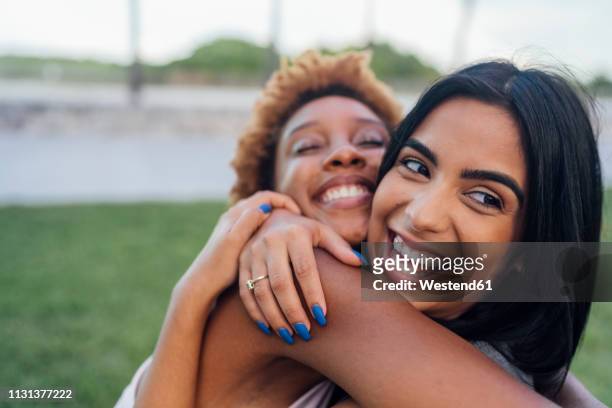 portrait of two happy female friends hugging in a park - alleen volwassenen stockfoto's en -beelden