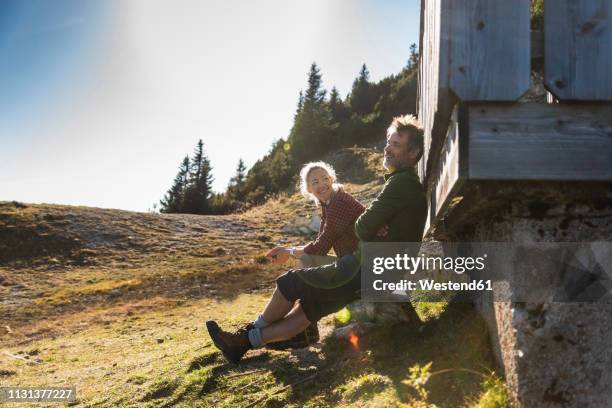 hiking couple sitting in front of mountain hut, taking a break - hut stockfoto's en -beelden