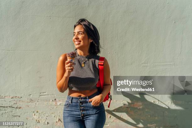 portrait of happy young woman with ice cream cone at a wall - cropped tops stock pictures, royalty-free photos & images