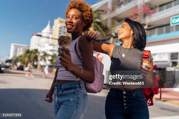 usa, florida, miami beach, two happy female friends with ice cream cones in the city - freundinnen urlaub sommer eis stock-fotos und bilder