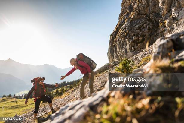 couple hiking in the austrian mountains - climbing help stock pictures, royalty-free photos & images