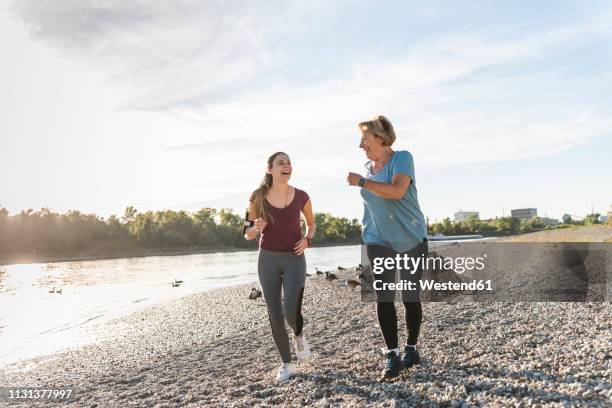 granddaughter and grandmother having fun, jogging together at the river - old woman running stock pictures, royalty-free photos & images