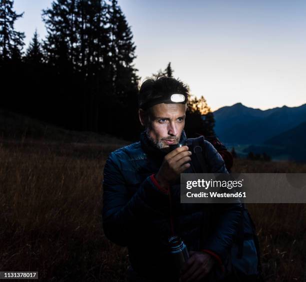 hiker with head lamp, drinking tea - stirnlampe stock-fotos und bilder