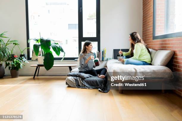 two happy young women having asian takeaway food at home - friends talking living room stock pictures, royalty-free photos & images