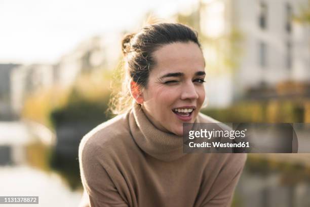 portrait of winking woman wearing light brown turtleneck pullover in autumn - winking fotografías e imágenes de stock