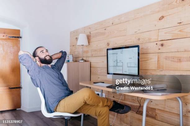 smiling young man sitting at desk with floor plan on the computer - leaning back stock pictures, royalty-free photos & images