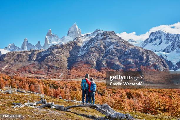 argentina, patagonia, el chalten, two boys on a hiking trip embracing at fitz roy massif - argentina travel stock pictures, royalty-free photos & images