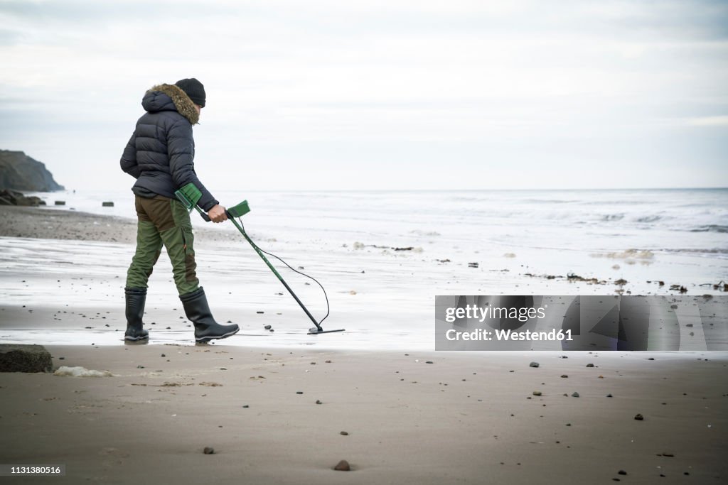 Man with metal detector at the sand beach
