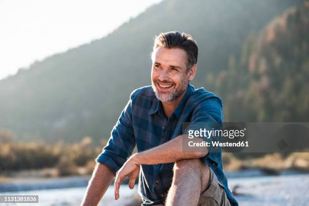 mature man camping at riverside - flannel shirt stock pictures, royalty-free photos & images
