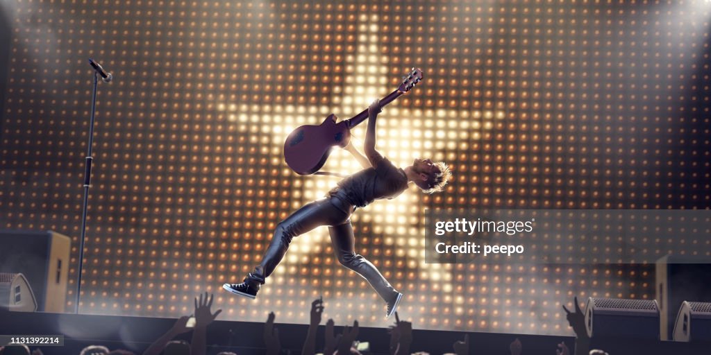 Rock Star In Mid Air Jump With Guitar On Stage