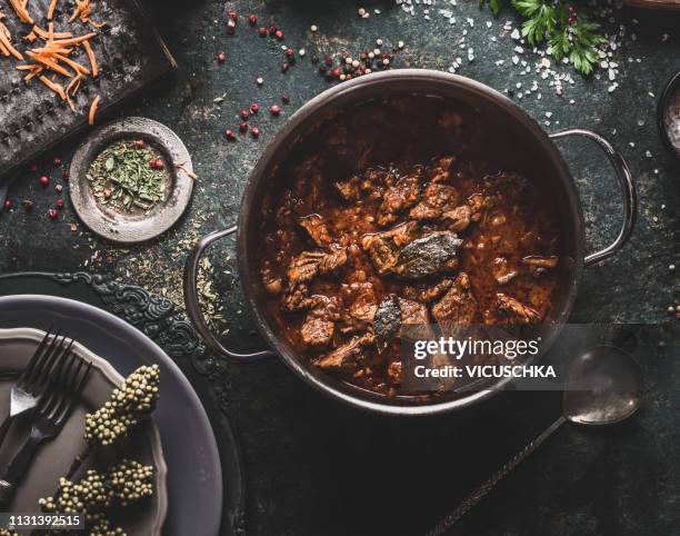 meat stew in cooking pot on dark rustic kitchen table background - rindfleischeintopf stock-fotos und bilder