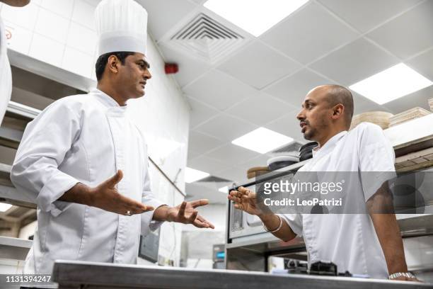indian chefs cooking in a professional kitchen of a gourmet restaurant - crowded kitchen stock pictures, royalty-free photos & images