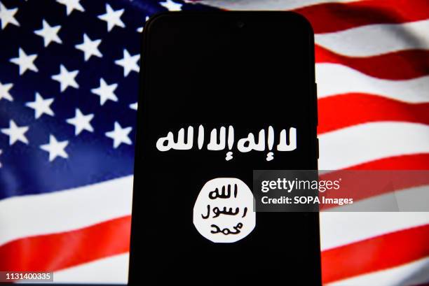 In this photo illustration, the Islamic State flag is seen displayed on an Android mobile phone with United States of America flag in the background.