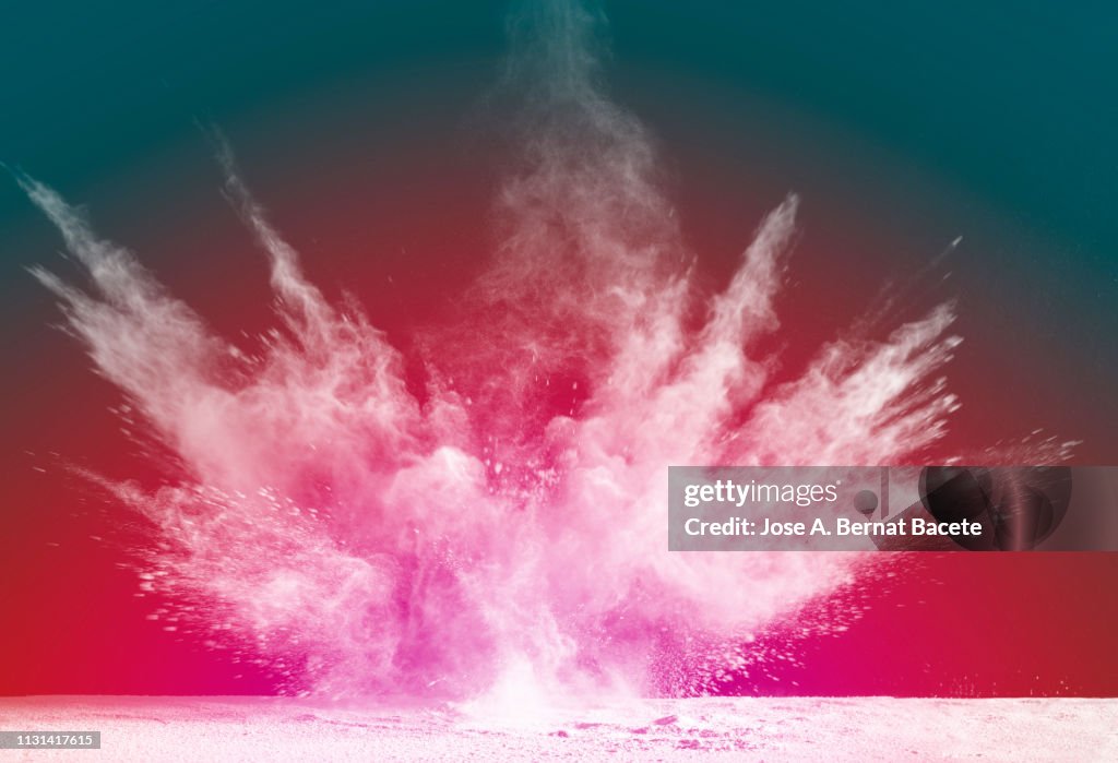 Explosion by an impact of a cloud of particles of powder and smoke of color white on a red background.