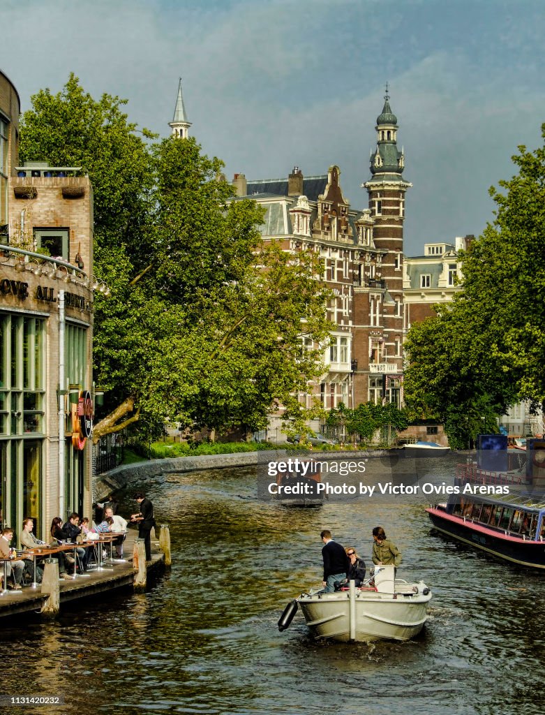 Typical image of a canal in Amsterdam in summer with boats bar terraces