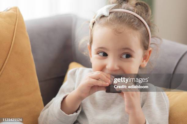 klein meisje dat chocolade eet - chocolate baby stockfoto's en -beelden