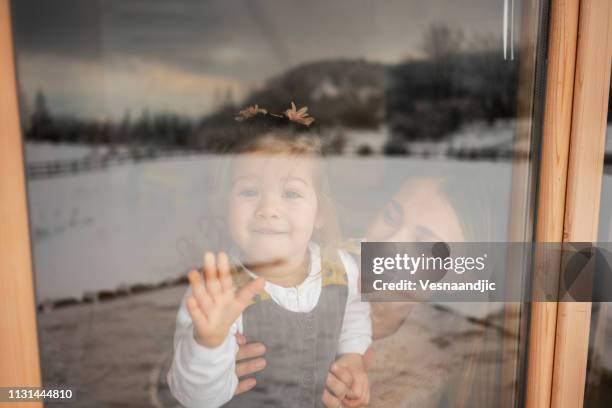 moeder en dochter kijken door raam - winter baby stockfoto's en -beelden