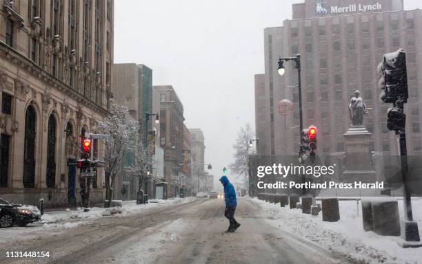 Pedestrian crosses Congress street in snow in the early morning on Monday, March 4, 2019.