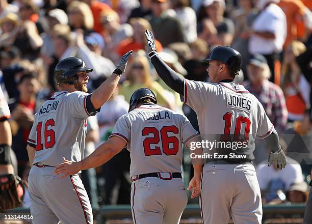 Brian McCann, Dan Uggla and Chipper Jones of the Atlanta Braves celebrate after Uggla and Jones scored in the 10th inning against the San Francisco...