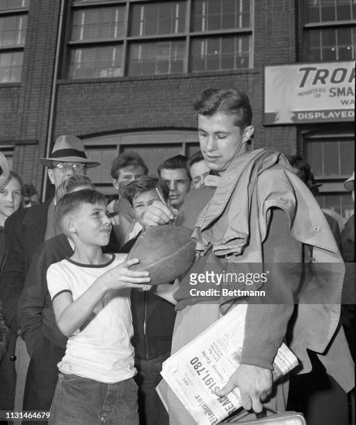 Frankie Sinkwich, ace passer for the University of Georgia team, autographs football for 12-year-old Clyde Wakelee as the Georgia team arrives at...