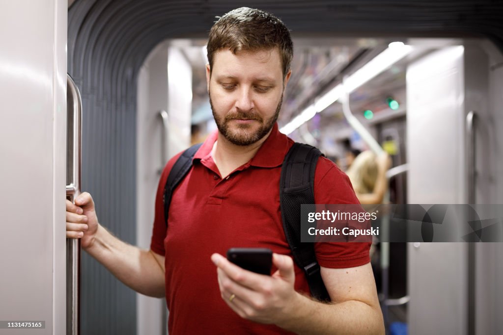 Homem que usa o telefone móvel no metro