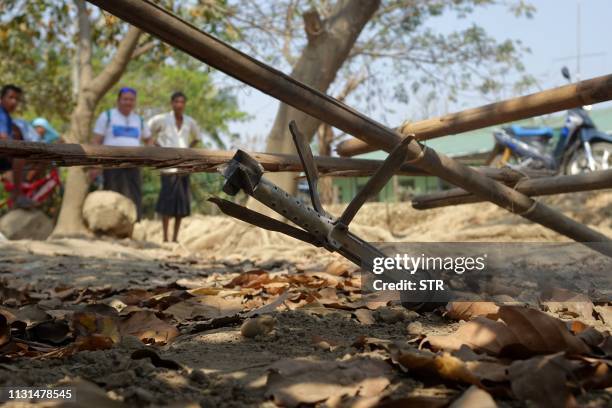 This photo taken on March 16, 2019 shows people looking at an unexploded rocket in the Mrauk U township in Rakhine. - Fighting between Myanmar's...